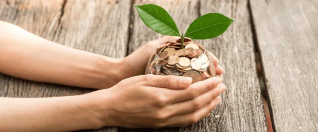 a hand is holding a glass of coins