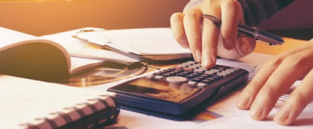Person at desk with notebooks, documents, and calculator