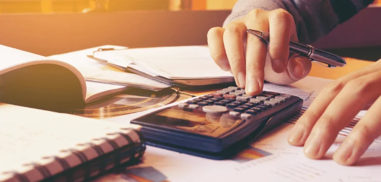 Person at desk with notebooks, documents, and calculator