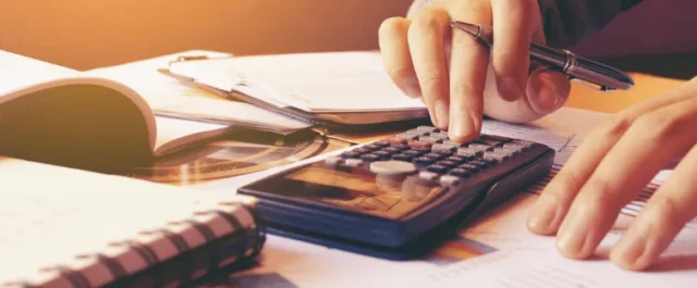 hand typing on a calculator and documents