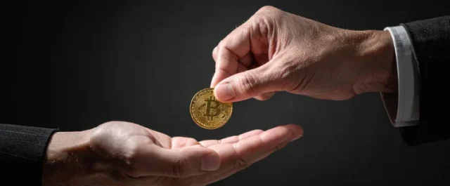 Zwei Hände, die sich eine Bitcoin Münze übergeben