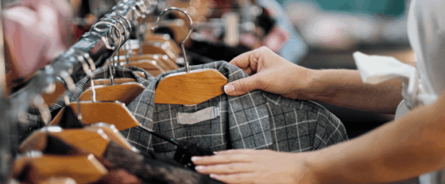 Frau nimmt Jacke von Kleiderstange