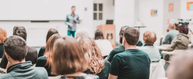 Mehrere Menschen in Rückansicht in einer Sitzung