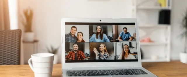 Laptopbildschirm zeigt mehrere Personen in einem Online-Meeting