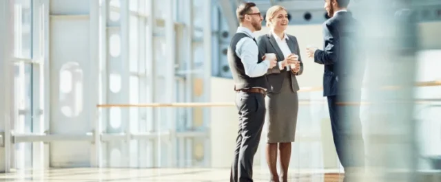 Three persons talking in an office corridor